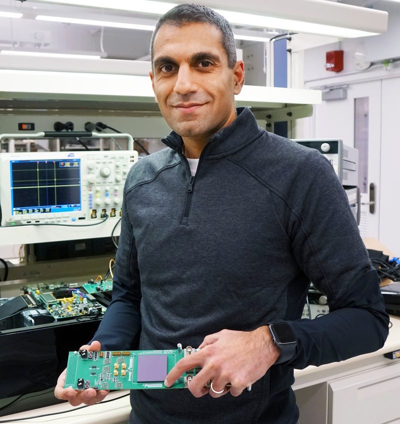 EnCharge AI联合创始人兼首席执行官纳文·维尔马(Naveen Verma)在普林斯顿大学的实验室里拿着该公司先进计算技术的原型机。